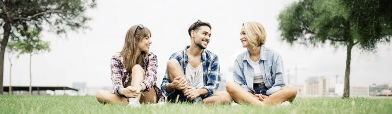 three people sitting on the grass